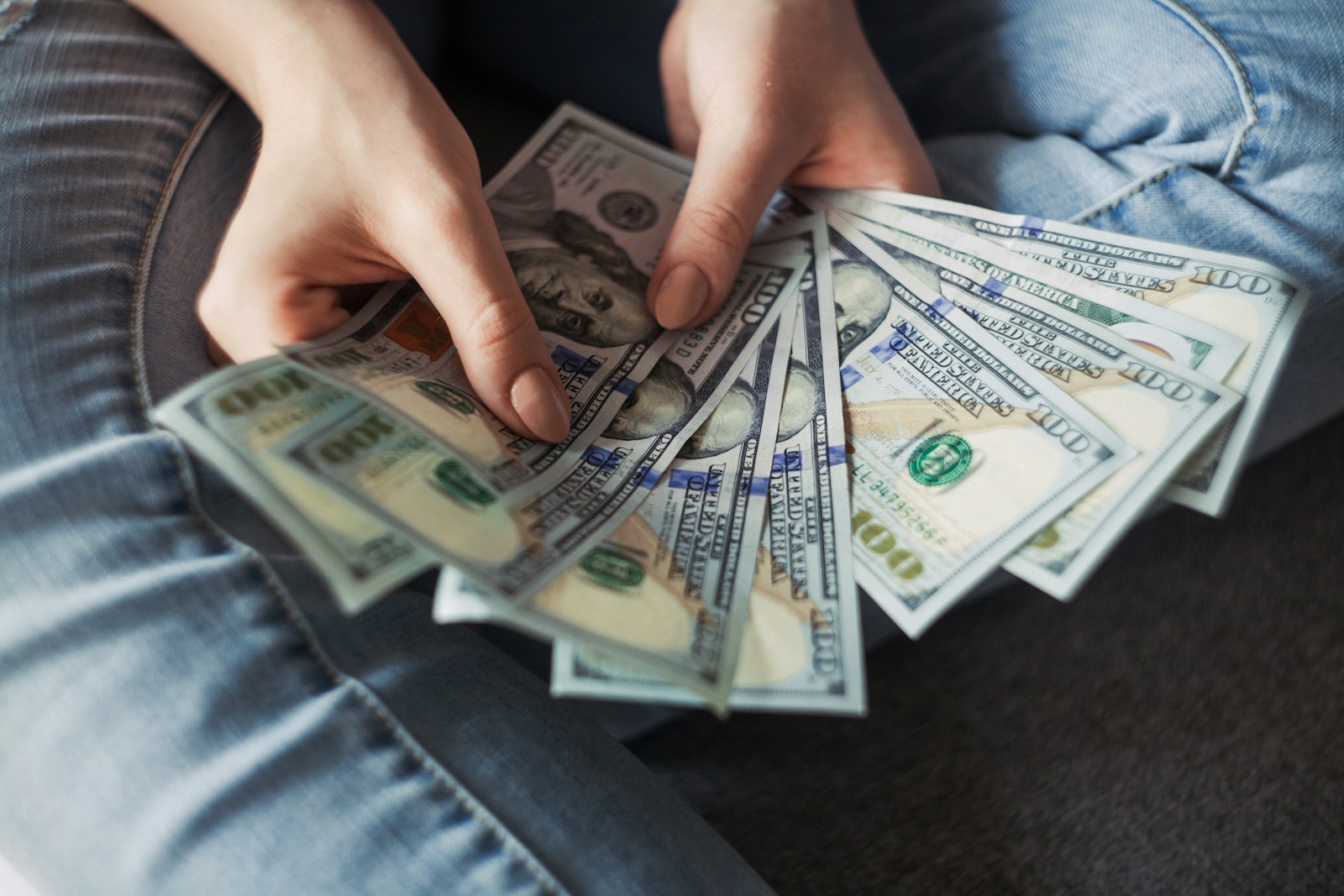 Someone holding a handful of American 100 Dollar Bills